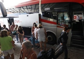 Viajeros cogiendo las maletas tras llegar en autobús desde Madrid.