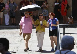 Dos turistas transitan por el casco histórico de la ciudad bajo un paraguas para protegerse del calor.