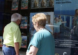 Un señor observa los viajes ofertados en un escaparate.