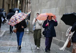 Viandantes resguardándose de la lluvia con un paraguas.