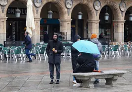 Algunos turistas se refugian de la lluvia en la Plaza Mayor.