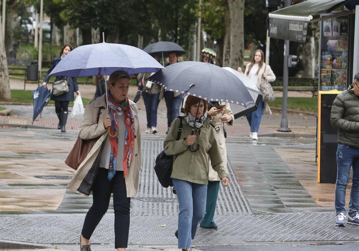 Dos paseantes, bajo la lluvia de este lunes en Salamanca.