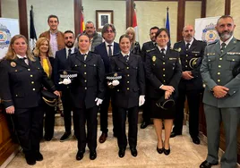 Foto de familia con las dos agentes en primer término acompañadas por parte de la Corporación municipal y las fuerzas de seguridad.