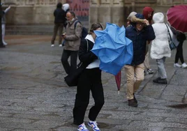 Una joven procede a cerrar su paraguas en Salamanca por el viento.