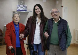 Flora Agustín y Pablo Salazar agarran con fuerza las manos de Carla Blanco, la estudiante voluntaria que les visita cada semana.