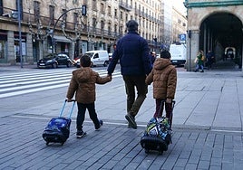 Dos niños, de camino al colegio con su padre.