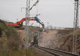 Una máquina acaba con el puente sobre la vía del tren situado junto al Puerto Seco