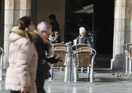 Dos personas van por la Plaza Mayor.