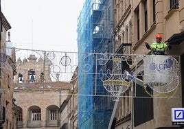 Un trabajador instalando un arco de luces en una de las calles del centro de la ciudad.