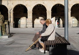 Dos personas mayores, sentadas en un banco del centro de Salamanca.