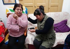 Milagros mira la fotografía de su hijo mientras llora desconsolada junto a una allegada.