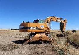 Una máquina excavadora realiza labores de limpieza de un vertido.