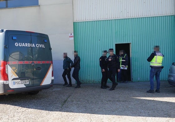 El detenido, vestido de negro, sale esposado de la nave en la calle Tierra de Campos.