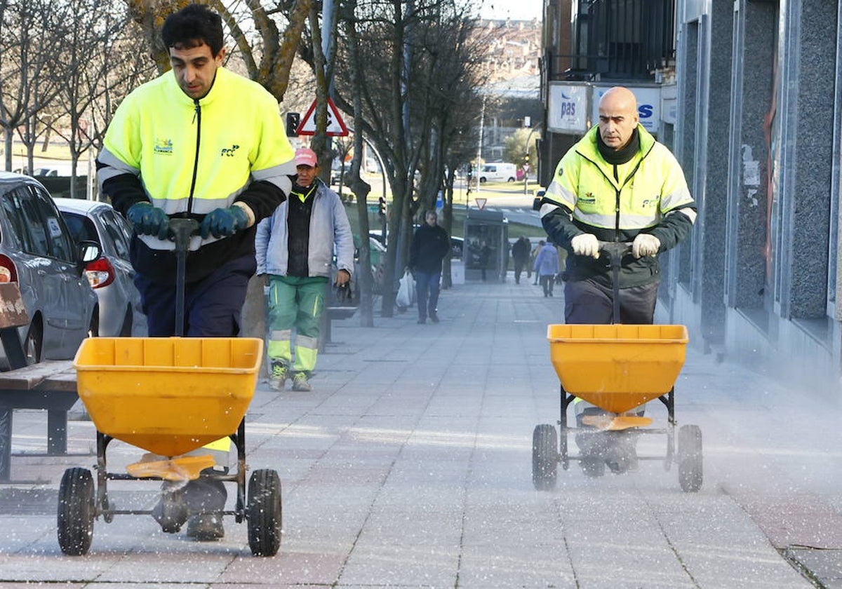 Dos operarios esparcen sal por la ciudad.