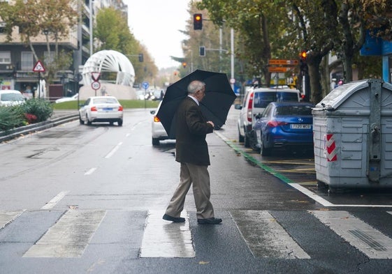 Un salmantino se cobija de la lluvia en la capital.