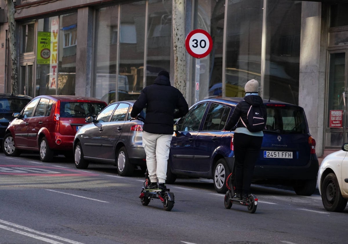 Una pareja circula con sendos patinetes eléctricos por una vía de la ciudad.