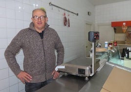 José Guerra posa junto a una báscula, tras el mostrador de su tradicional tienda de alimentación.