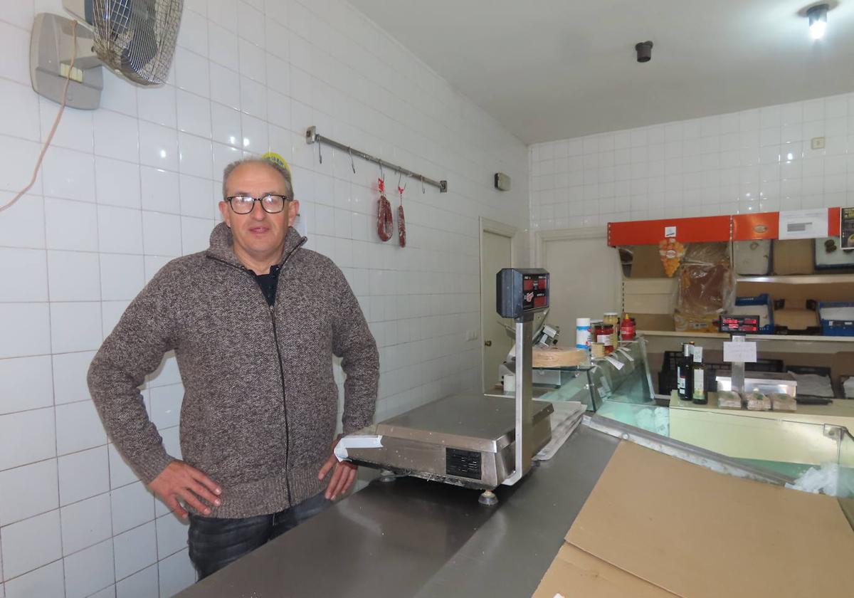 José Guerra posa junto a una báscula, tras el mostrador de su tradicional tienda de alimentación.