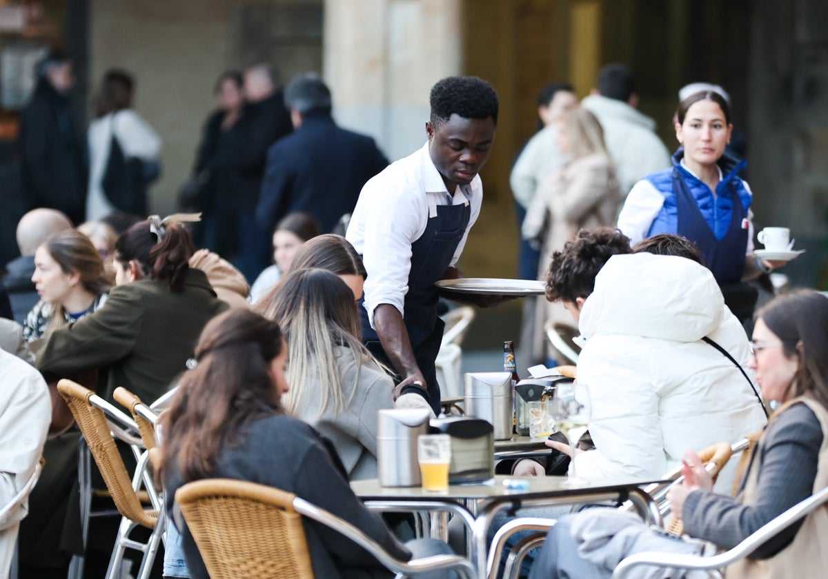 Un camarero de un establecimiento de la Plaza Mayor atiende la mesa de una terraza.