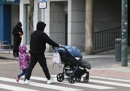 Un padre con un niño de la mano y un carrito de la otra.