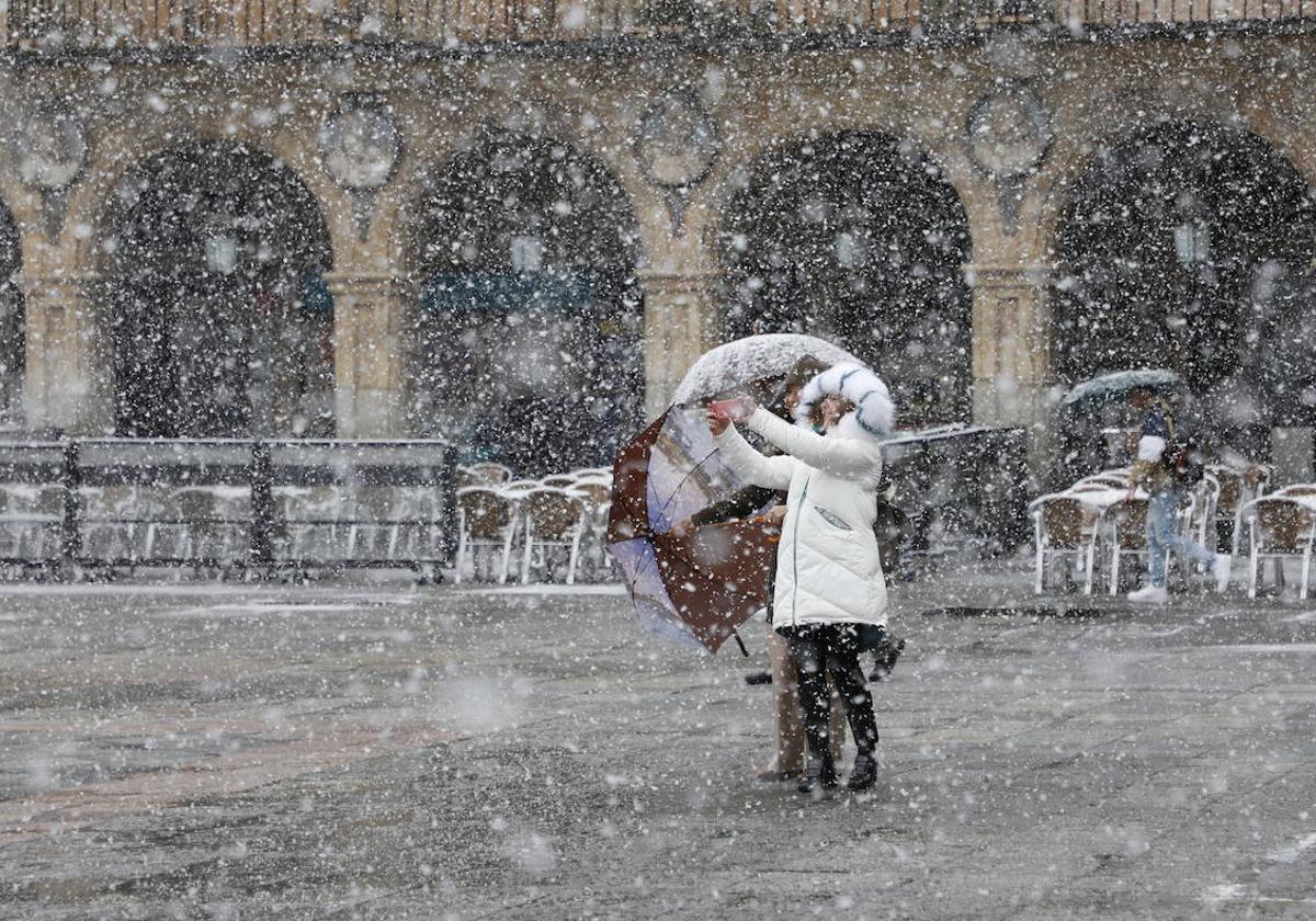 Una mujer bajo la nieve en la Plaza Mayor de Salamanca.