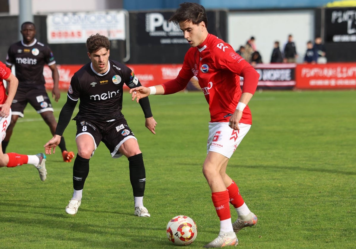 Amaro, primer goleador del día, defiende a un jugador del CD Laredo.