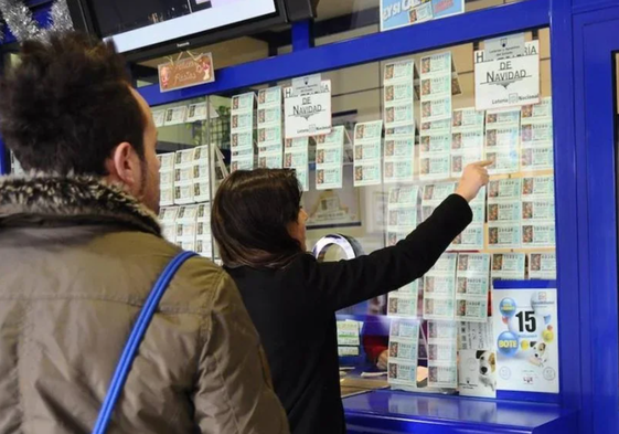 Dos personas acuden a una administración de loterías.
