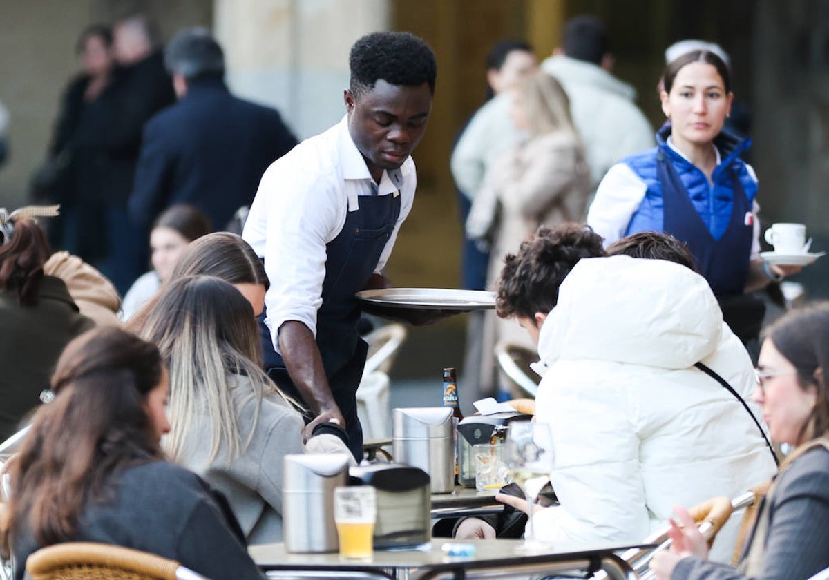 Un camarero atiende a clientes de una terraza de la Plaza Mayor.