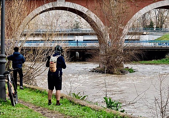 Dos personas observan el río Manzanares a su paso por el puente de los Franceses.