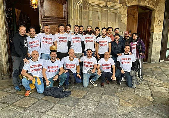 Bomberos en la puerta de salón de plenos con camisetas de 'Bomberos quemados', este viernes.