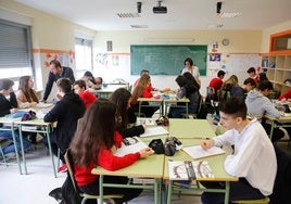 Dos profesores atienden a un grupo de alumnos en clase.