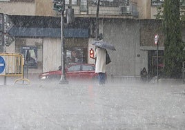 Una joven se refugia bajo su paraguas.