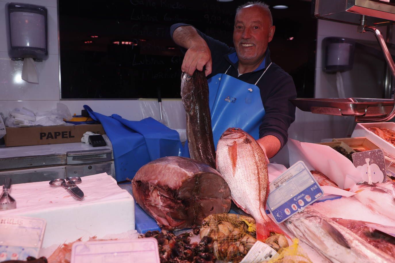 Un pescadero coge dos de los productos que han entrado en las pescaderías del Mercado esta semana.