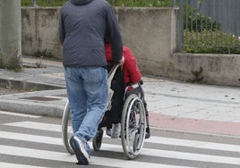 Un hombre ayuda a una persona de silla de ruedas a cruzar la calle.