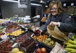 Nati Rodríguez cogiendo unas cerezas en su puesto del Mercado Central.