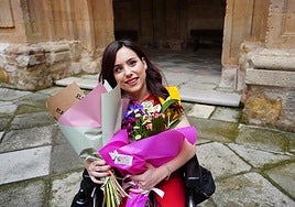 Paula Vega, con dos ramos de flores, tras recibir la beca como graduada en Logopedia en el claustro barroco de la Universidad Pontificia.