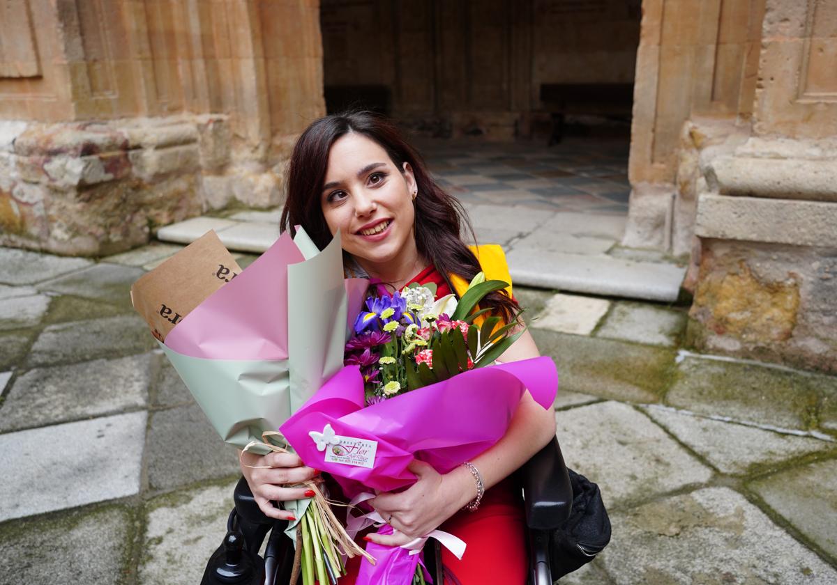 Paula Vega, con dos ramos de flores, tras recibir la beca como graduada en Logopedia en el claustro barroco de la Universidad Pontificia.