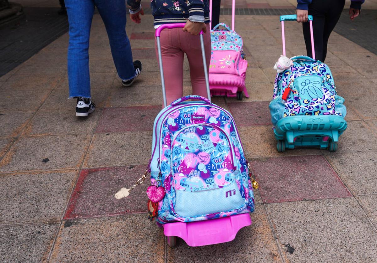 Varias niñas salen de su centro escolar con sus mochilas.