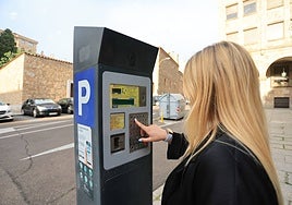 Una mujer se dispone a sacar un ticket de la ORA en un parquímetro.