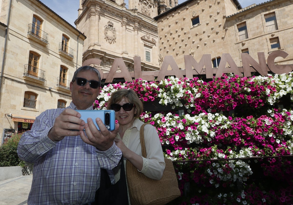 Una pareja se toma una selfie frente al 'photocall' floral ubicado en la Rúa Mayor.