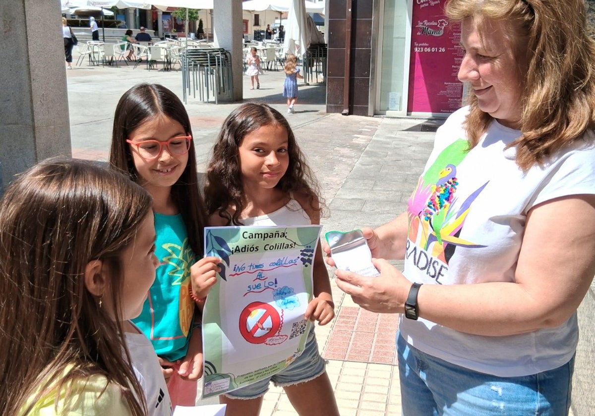 Los niños informando a una vecina de la campaña 'Adiós colillas'.