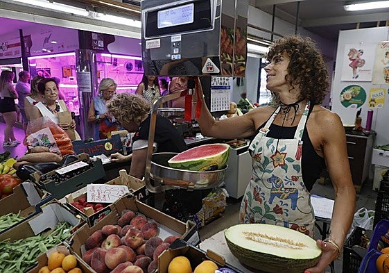 Susana, frutera del Mercado, pesa una sandía en su estand.