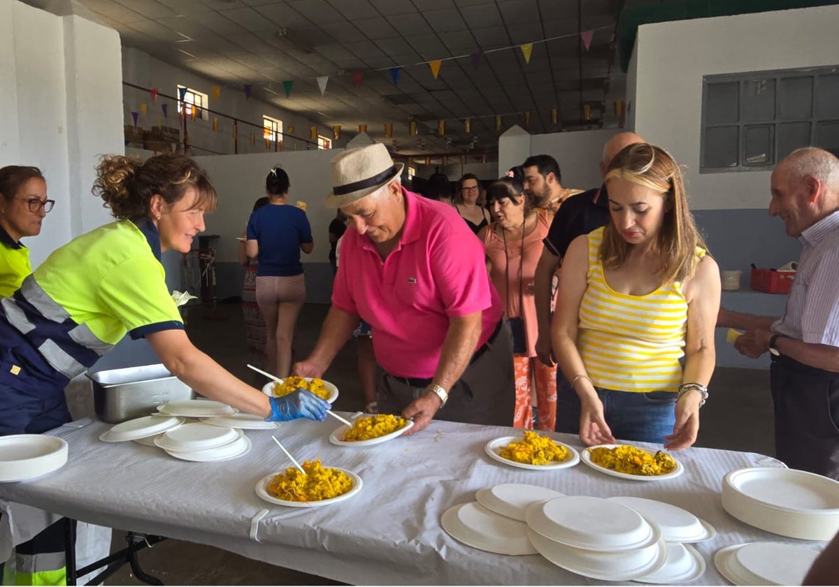 Los vecinos del municipio recogiendo su plato de paella en el centro polivalente.