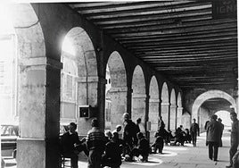 Actividad intensa en los Portales de San Antonio. Una «batería» de limpiabotas atiende a la clientela mientras varios paisanos esperan su turno.