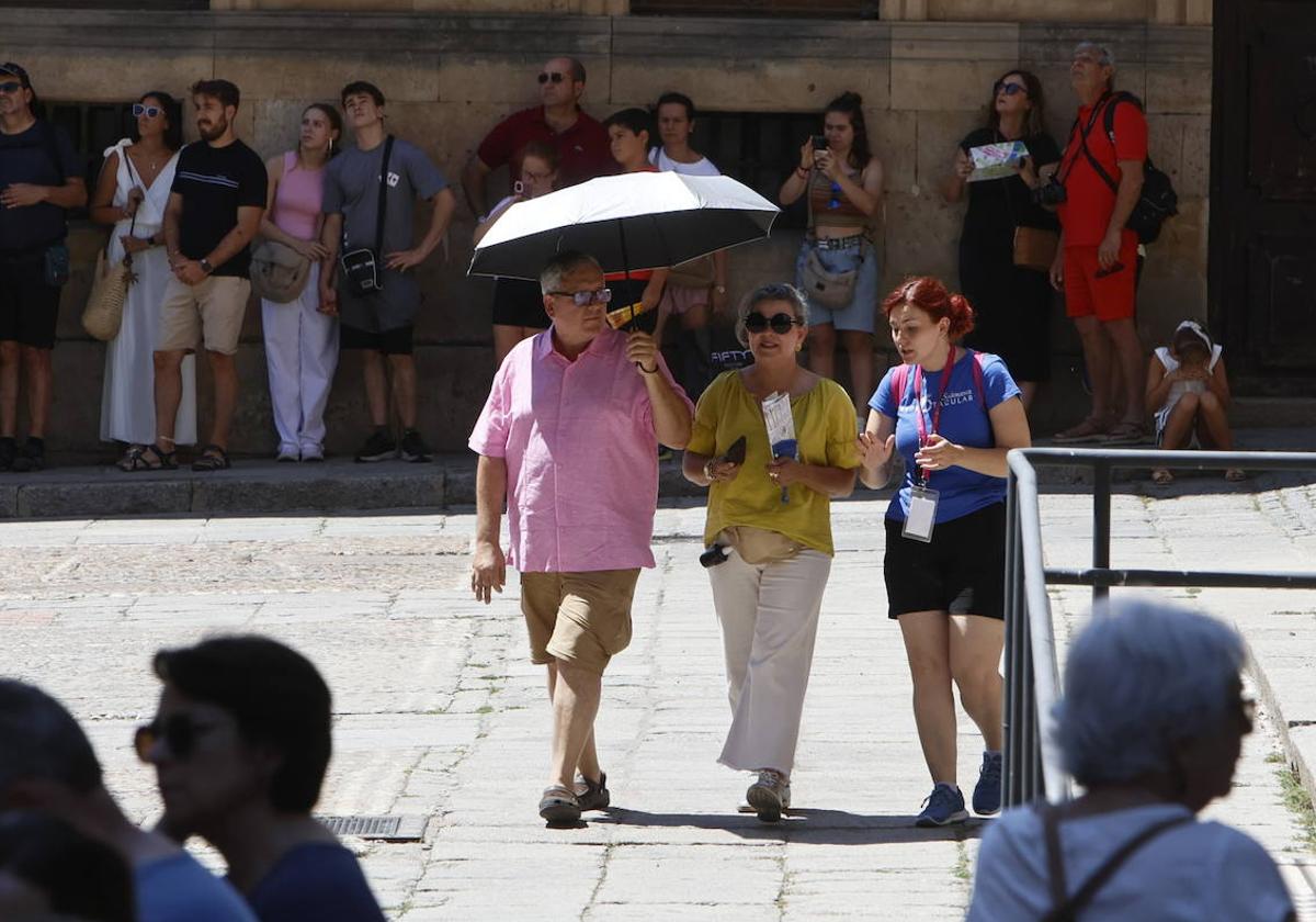 Dos turistas y una guía, bajo el sol en el casco histórico de Salamanca.