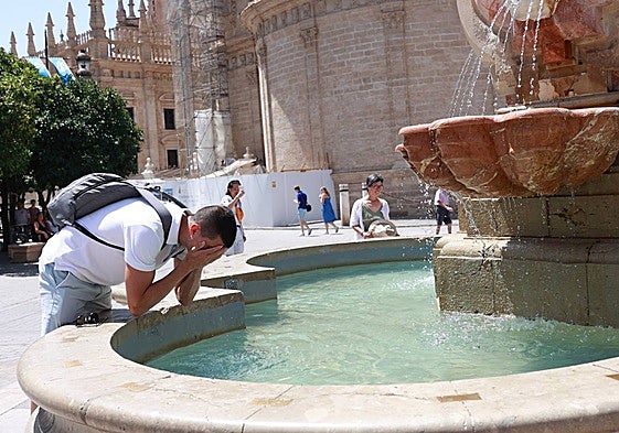 Un joven se refresca en una fuente para soportar las altas temperaturas.