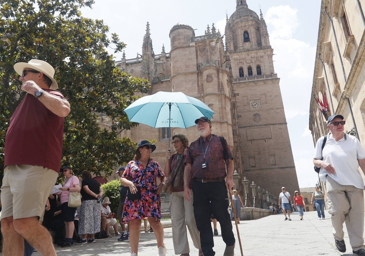 Turistas se protegen del sol bajo un paraguas en la plaza de Anaya.