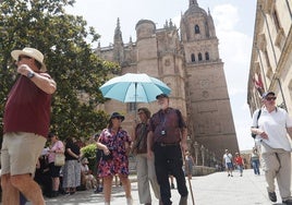 Turistas se protegen del sol bajo un paraguas en la plaza de Anaya.