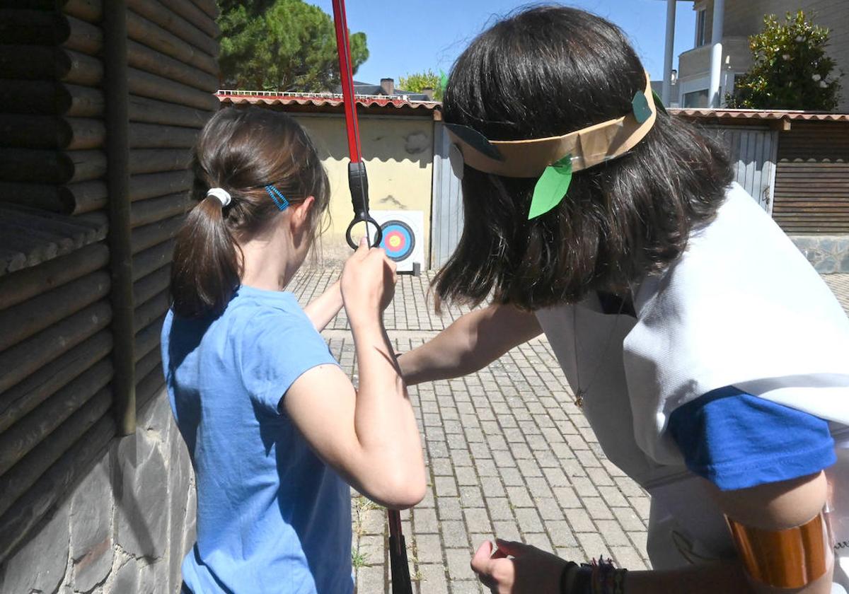 La monitora enseñando a una niña a realizar tiro con arco.