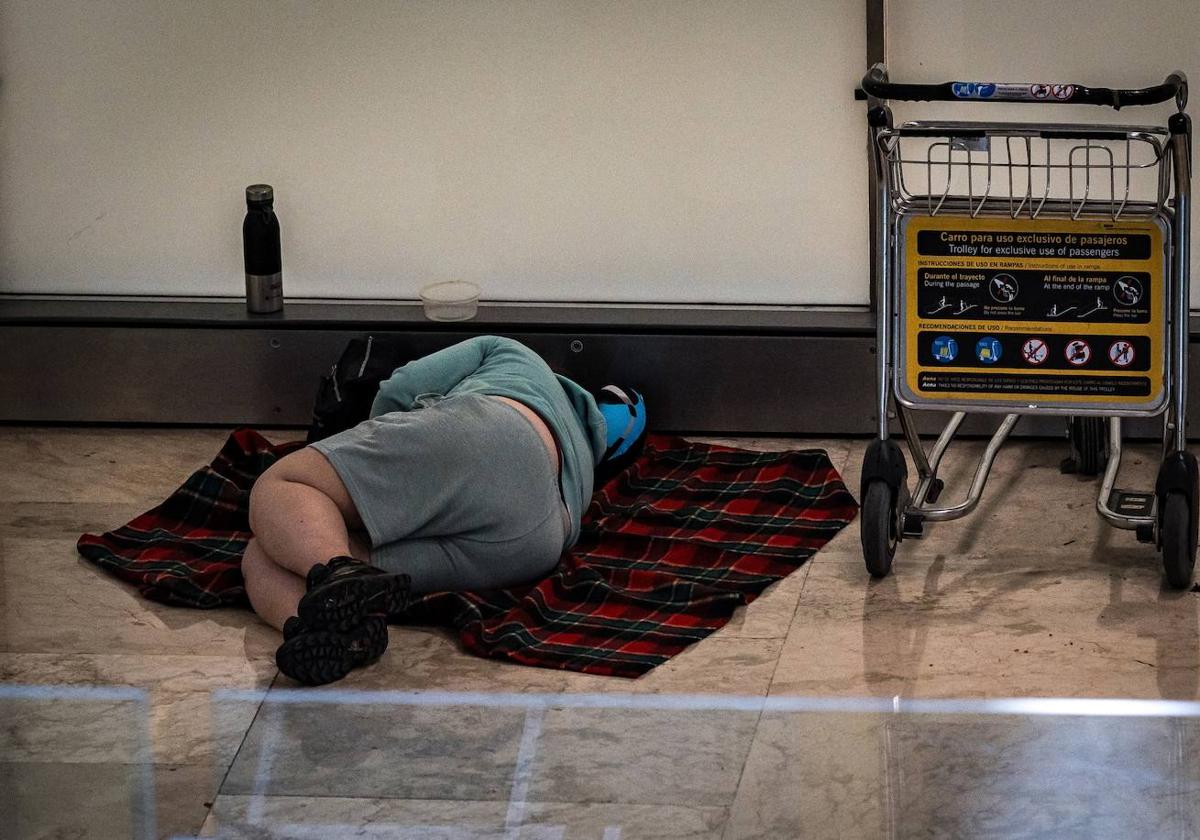 Una persona duerme en la T4 del Aeropuerto Adolfo Suárez.